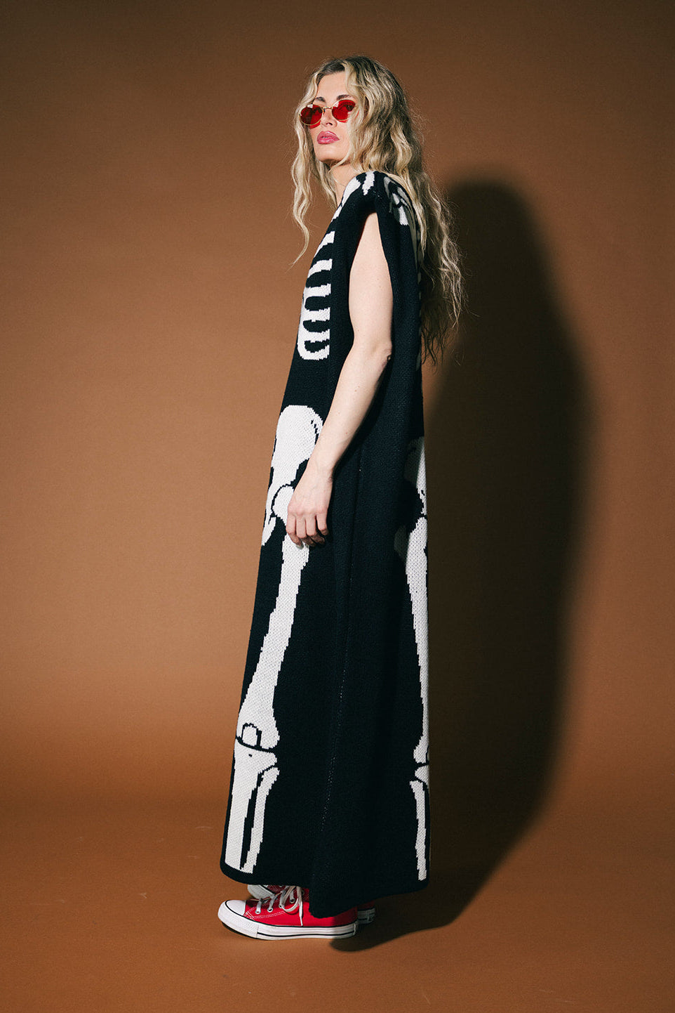 Person wearing a black dress with white skeleton design against a brown background