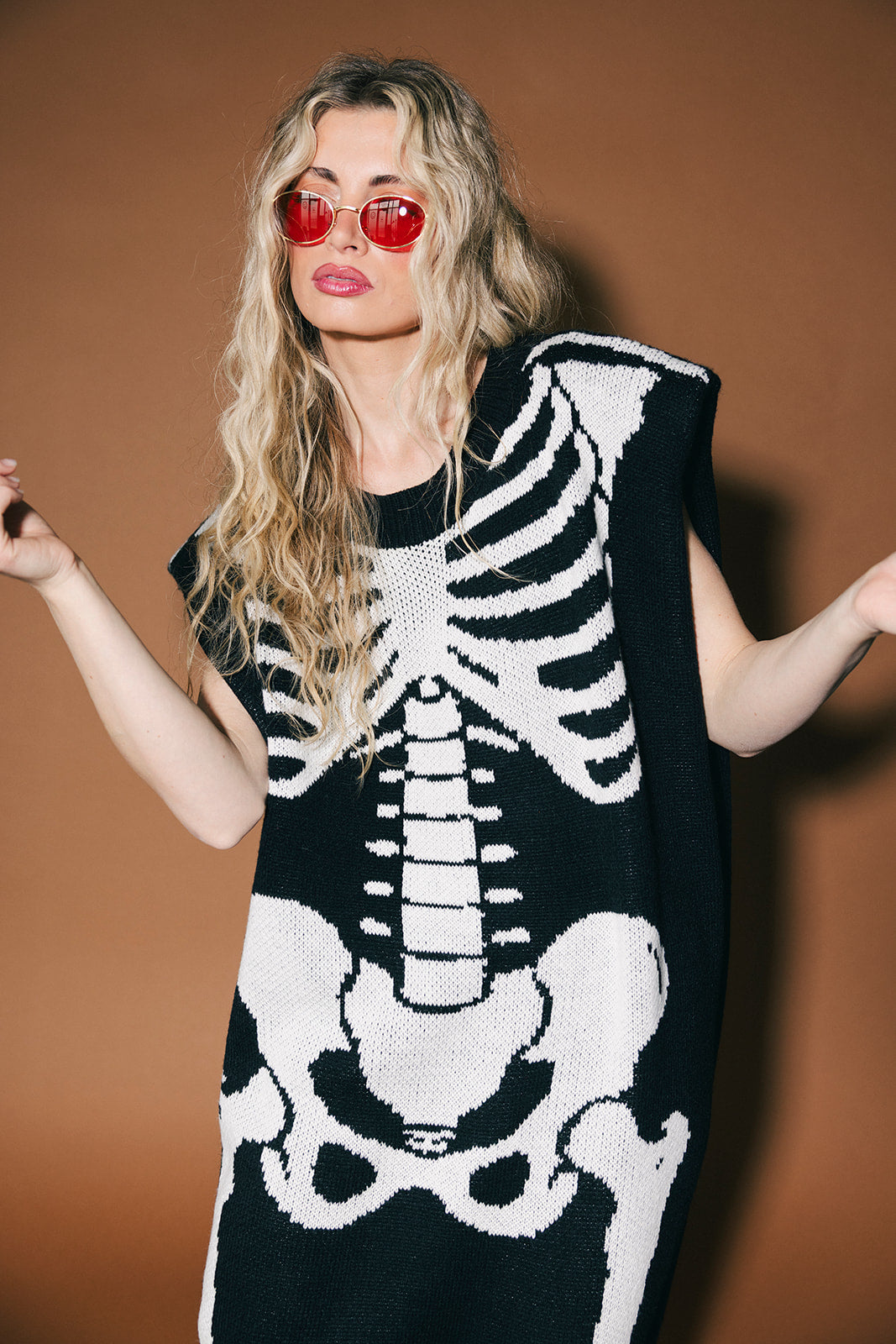 Person wearing a black and white skeleton-patterned outfit against a brown background