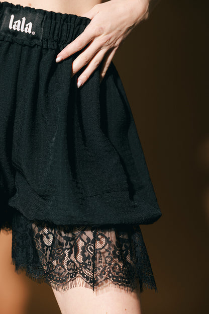 Black lace-trimmed shorts with 'lala' branding on a brown background