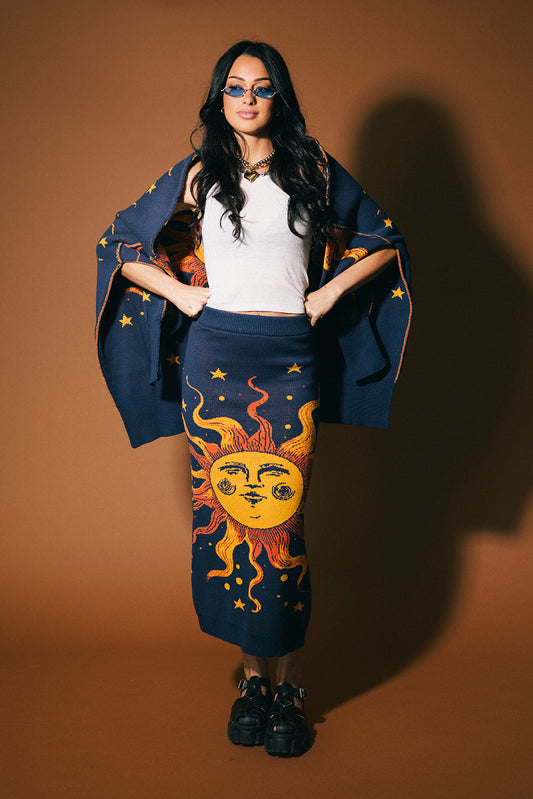 Woman wearing a blue cape with sun and moon designs on a brown background