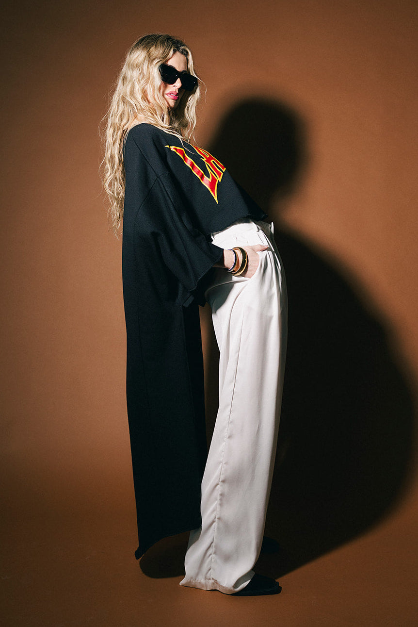 Person wearing a black outfit with a red logo on a brown background