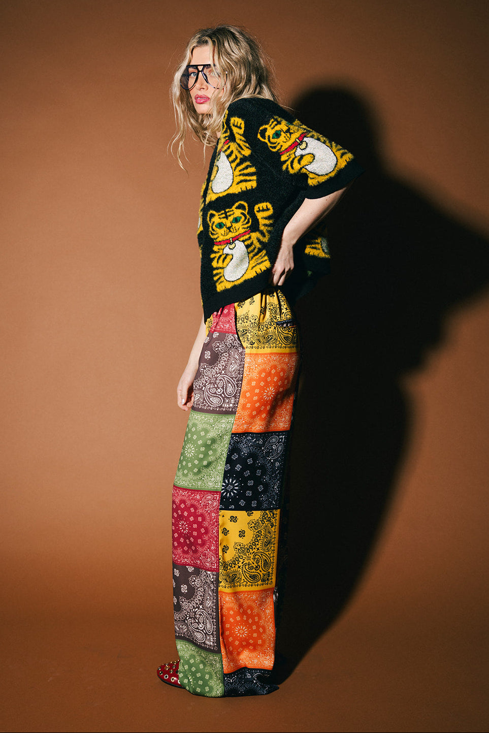 Person wearing a colorful patterned outfit with a brown background