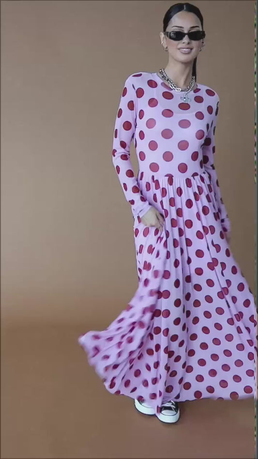 Video of woman wearing a pink mesh maxi dress with polka dots against a brown backdrop.