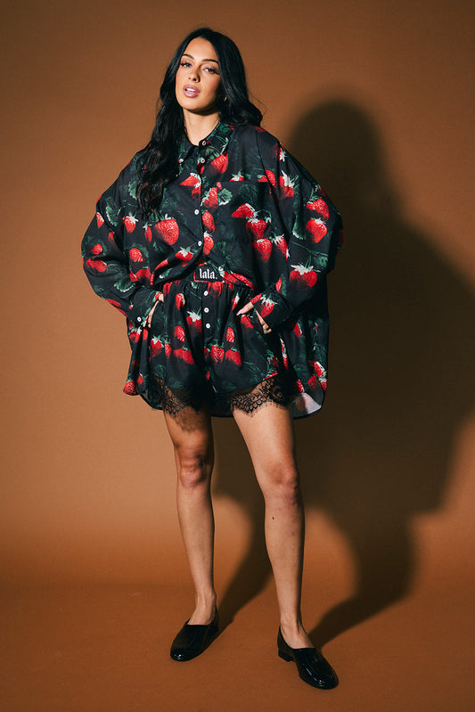Woman wearing a black strawberry shirt against a brown background