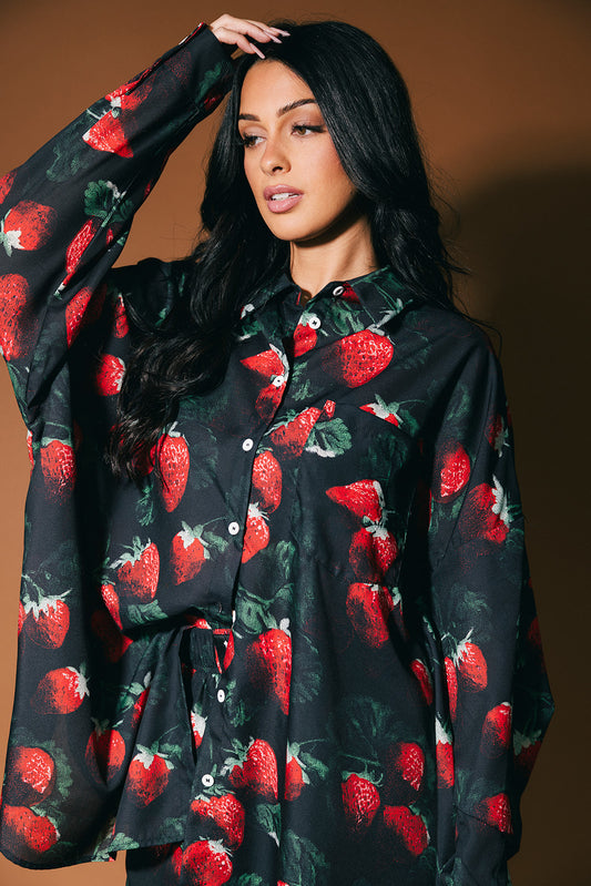 Woman wearing a black shirt with red strawberry pattern against a brown background